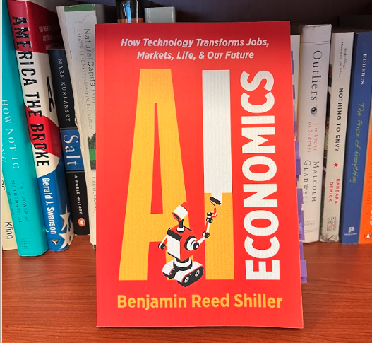 AI Economics book by Benjamin Reed Shiller standing upright on a bookshelf alongside Outliers, Freakonomics, and other titles