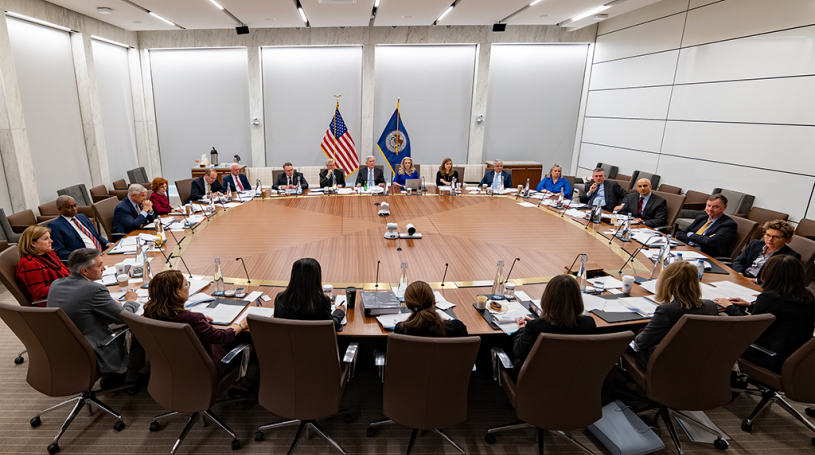 Attendees seated around a large table at a meeting of the Federal Open Market Committee