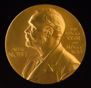 The Nobel Prize medal, featuring a relief portrait of Alfred Nobel with his name and birth and death years inscribed in Latin.”