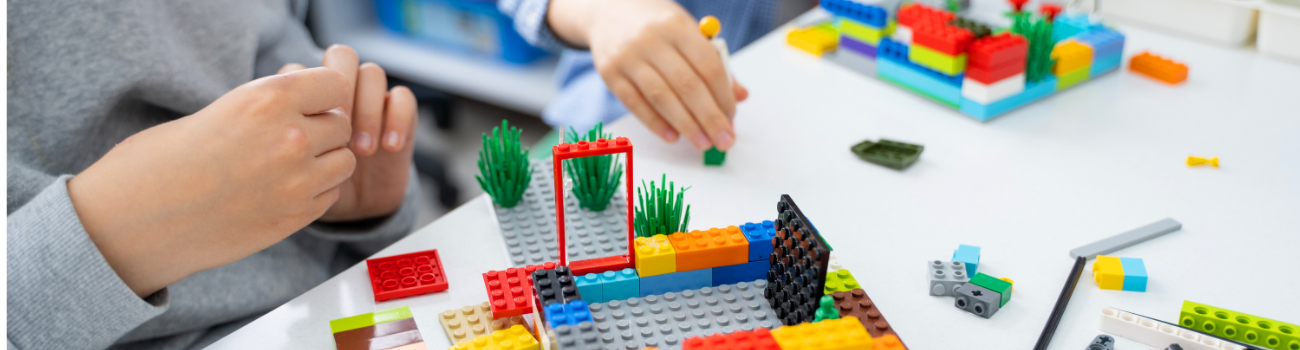 Two children play with colorful lego blocks in a visual representation of the Lesson 2.12 externality scenarios.