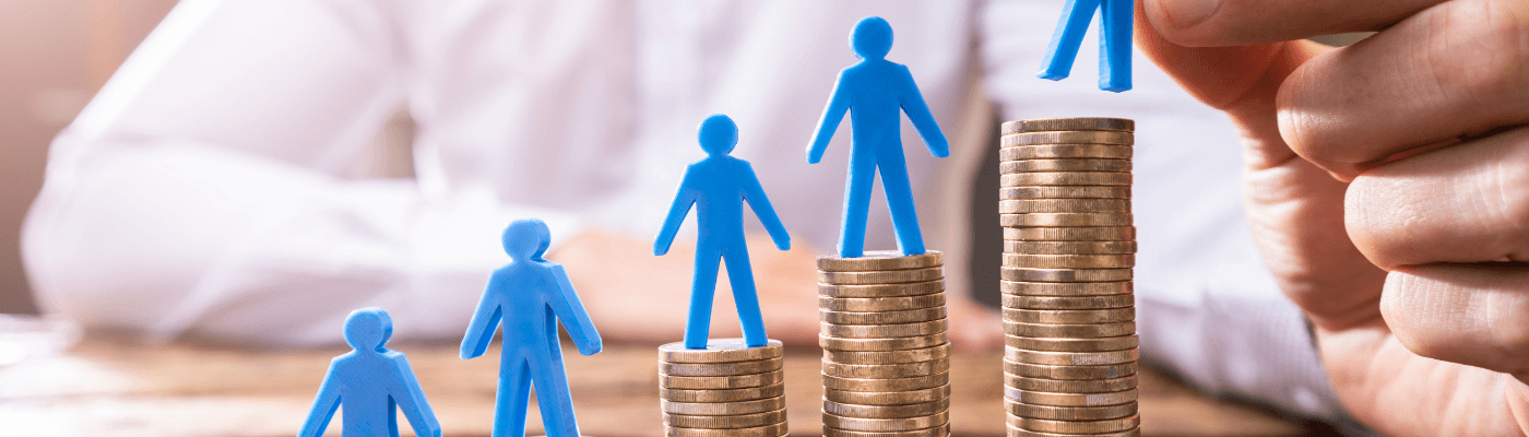 Four blue figures stand on progressively taller stacks of coins, illustrating growing income inequality, while a hand places a fifth figure on the tallest stack.