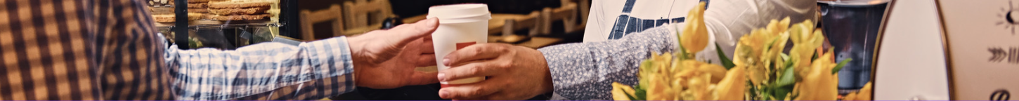 A barista hands a customer a cup of coffee in a demonstration of the law of demand.