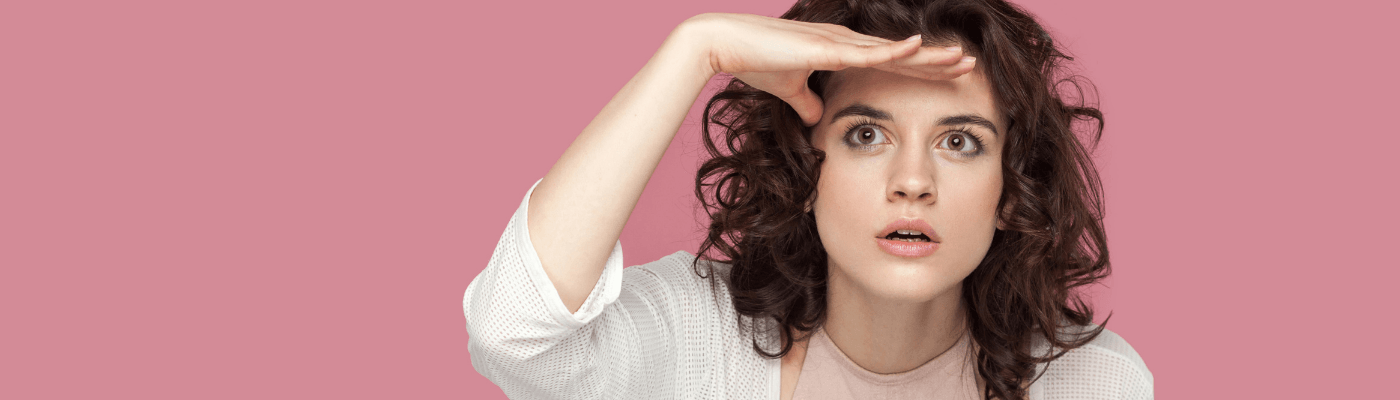 A young woman shades her eyes with her hand and looks intently into the distance against a pink background, illustrating the idea of spotting economics in plain sight.