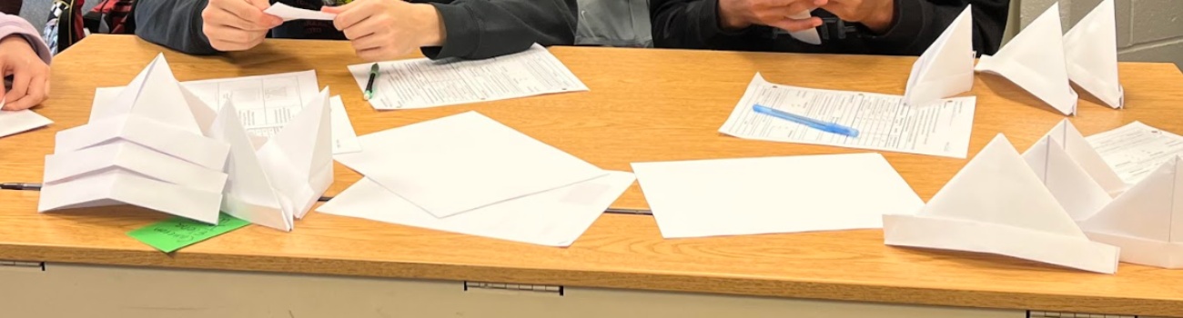 Students work on their paper hats together in the firm simulation exercise in lesson 2.3.