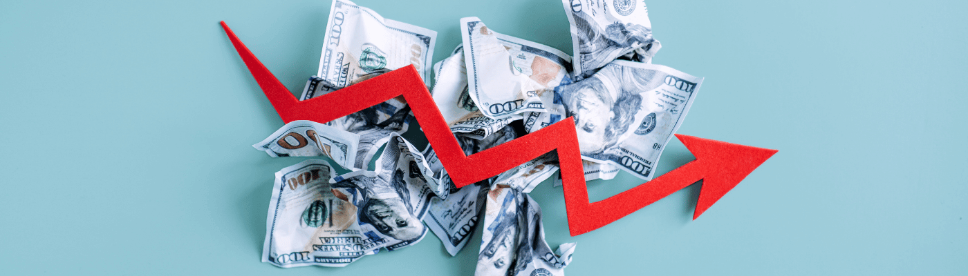 **Alt text:** `A red zigzag arrow indicating economic fluctuations overlays a pile of crumpled U.S. hundred-dollar bills, representing volatility in key macroeconomic indicators.`