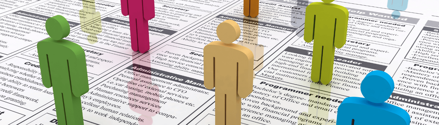 Colorful human figures of different colors stand on a newspaper covered in job listings, representing the diverse groups that experience unemployment at different rates explored in this lesson.