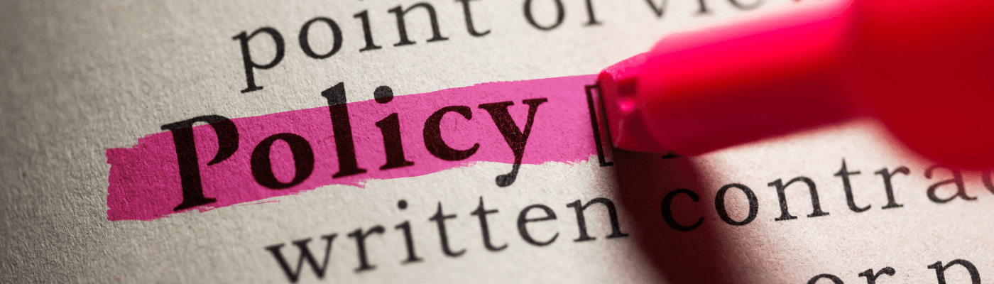 The word "Policy" highlighted in pink on a dictionary page, representing the policy analysis and evaluation students complete in this end-of-unit summative assessment.