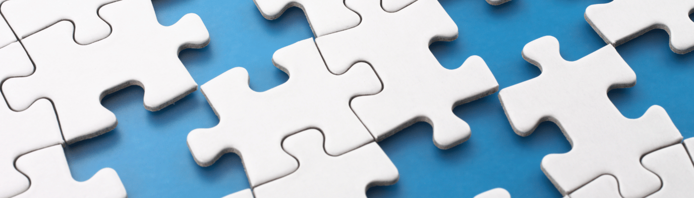 A grid of white jigsaw puzzle pieces fitting together against a blue background, forming a nearly complete picture with a few gaps still visible along the edges.