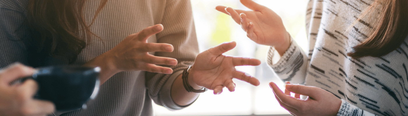 A group of people engaged in an animated discussion, with multiple hands gesturing expressively, illustrating the debate and competing perspectives involved in fiscal and monetary policy decisions.