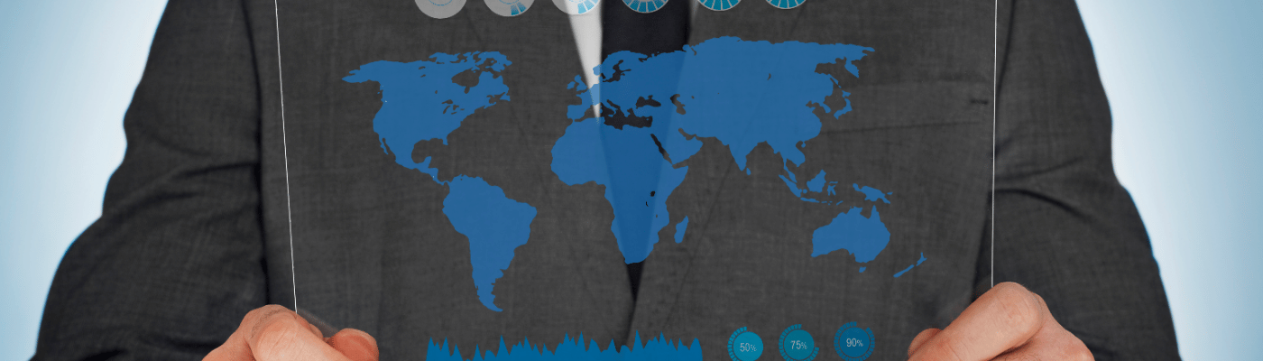 A person in a suit holding a transparent panel displaying a blue world map overlaid with economic data charts, progress indicators, and global statistics, representing the analysis of macroeconomic indicators across the economy