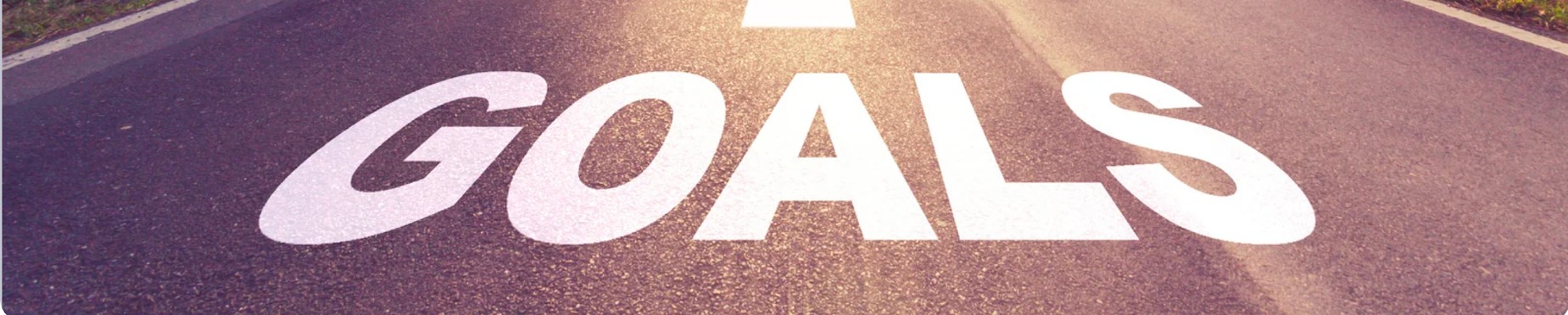 GOALS written in white letting across a roadway to denote the value of setting SMART Goals in personal finance.