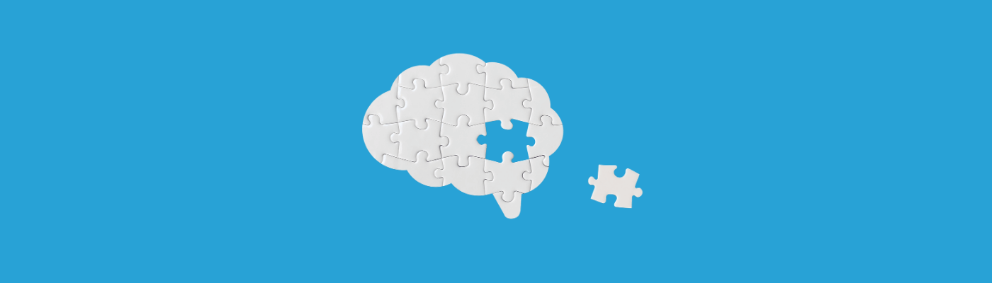 A missing puzzle piece sits outside a puzzle in the shape of a brain to show cognitive biases in personal finance.